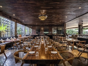 A restaurant with a long wooden table, multiple chairs, and a stone wall.
