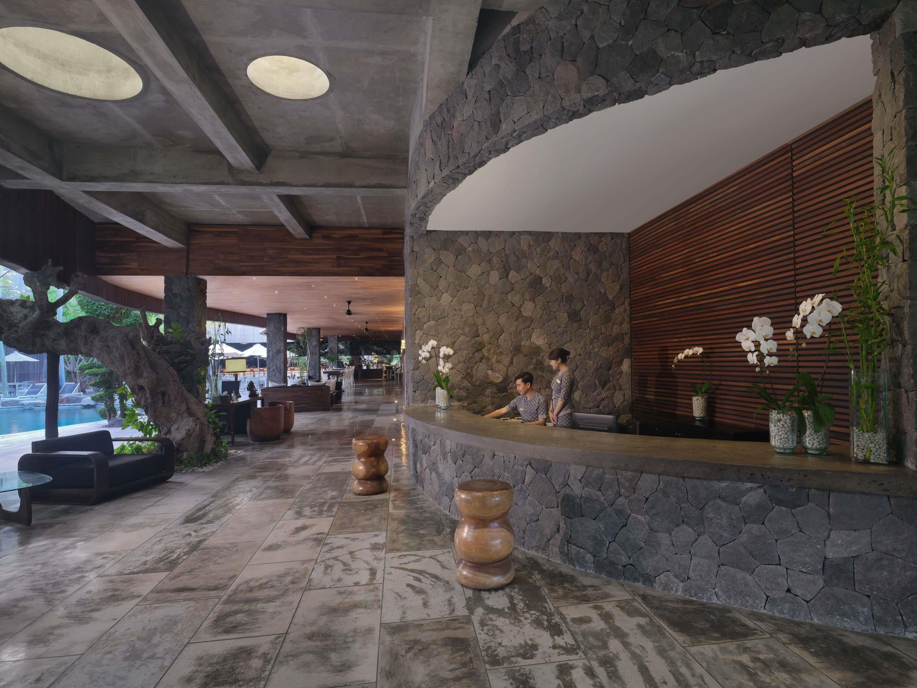 A reception area with a stone wall, wooden reception desk, and a view of the pool.