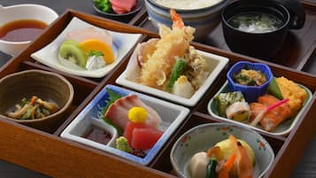 Una tradizionale scatola bento giapponese con diversi piatti, tra cui sushi, sashimi e verdure sottaceto.
