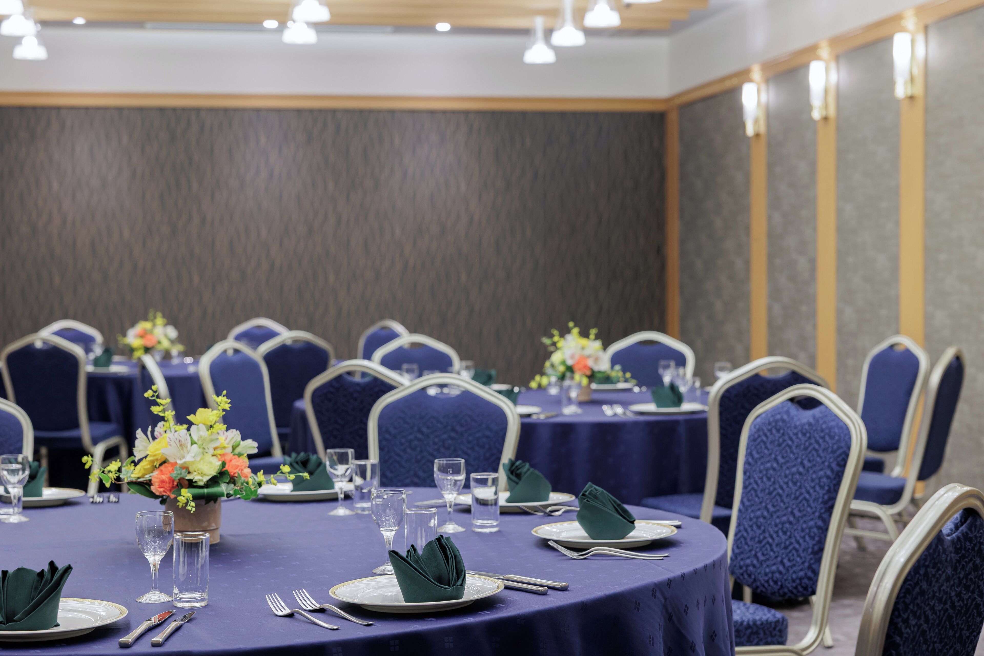 A conference room with round tables, chairs, and floral centerpieces.