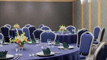 A conference room with round tables, chairs, and floral centerpieces.