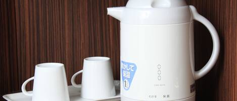 A white electric kettle with a lid, a tray, and two white cups.