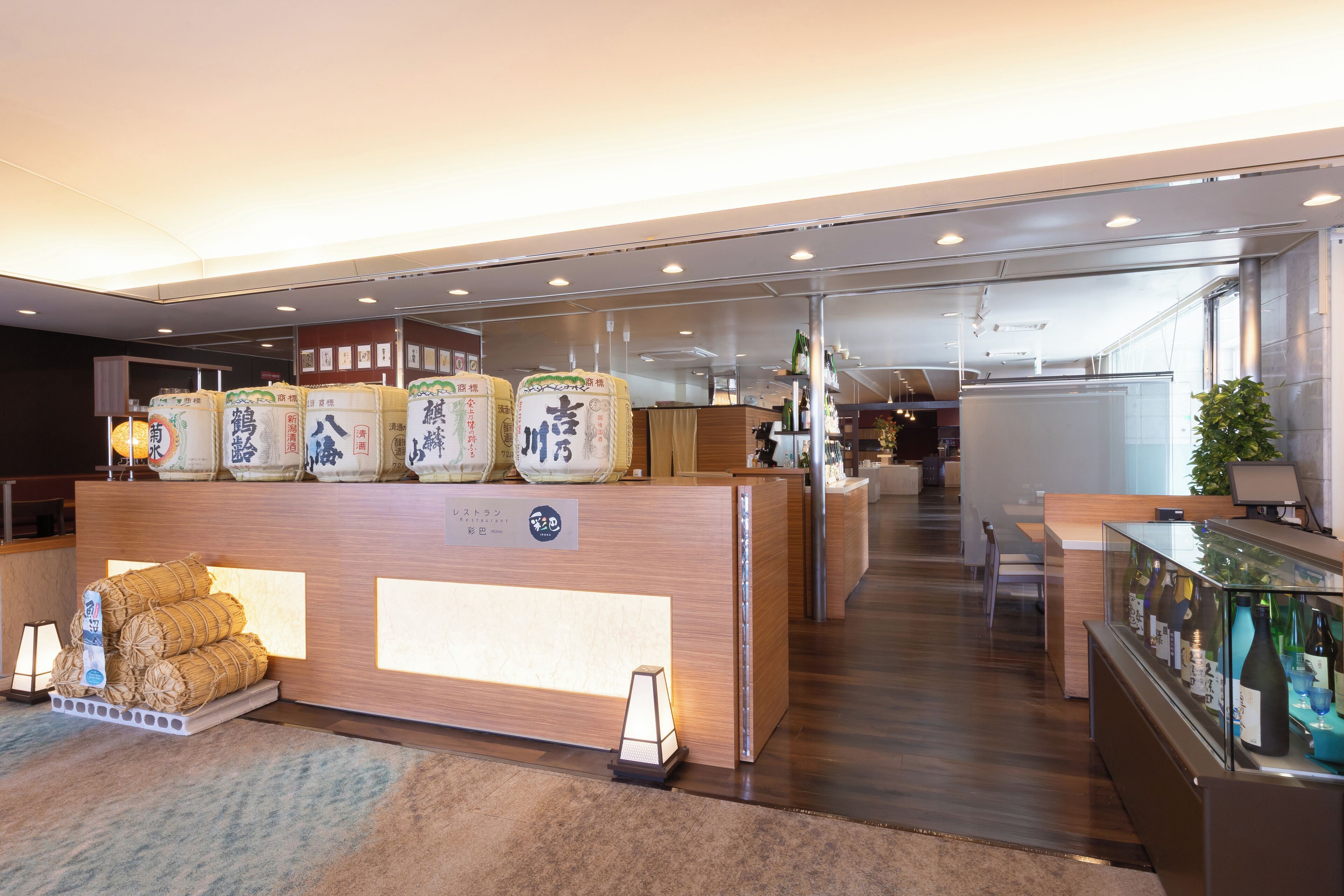A reception area with a wooden counter, traditional Japanese goods, and a wine display.