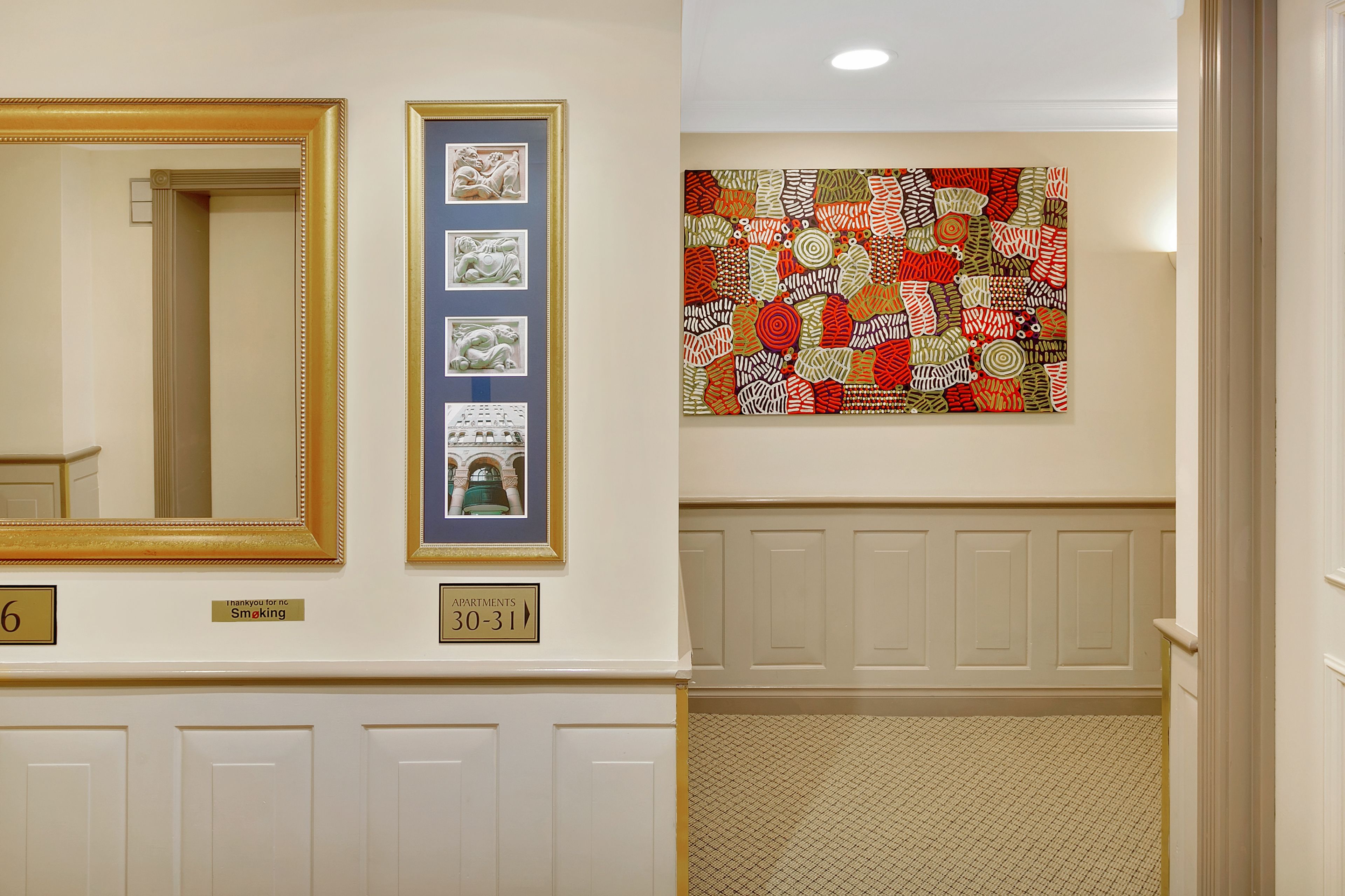 A hallway with a large mirror, framed artwork, and a colorful abstract painting.
