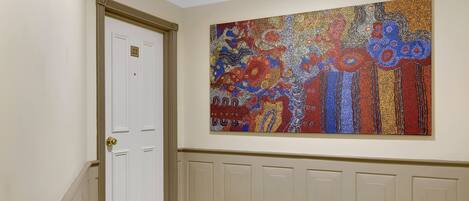 A hallway with a white door marked "22" and a large mosaic artwork on the wall.