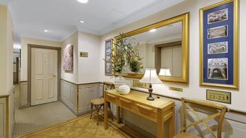 Um corredor com um console de madeira, um espelho e uma cadeira. Há quadros nas paredes e uma placa indicando '4º andar'.