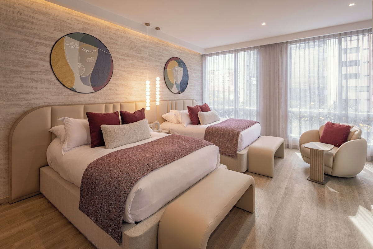 Una habitación de hotel moderna con dos camas, un sofá y una silla.