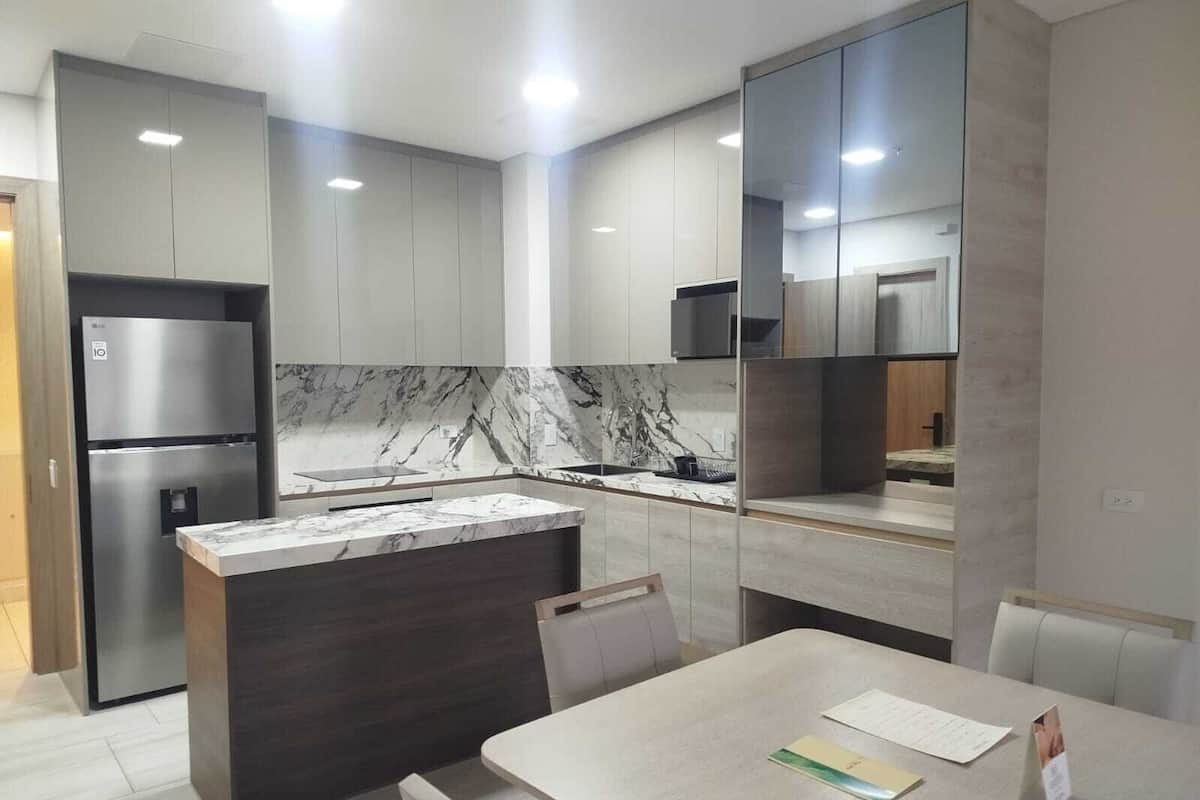 Una cocina moderna con una isla de mármol, electrodomésticos integrados y un comedor con mesa y sillas.