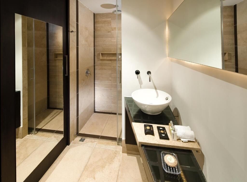 A modern bathroom with a glass-enclosed shower, a white sink with a vessel, and a vanity with toiletries.