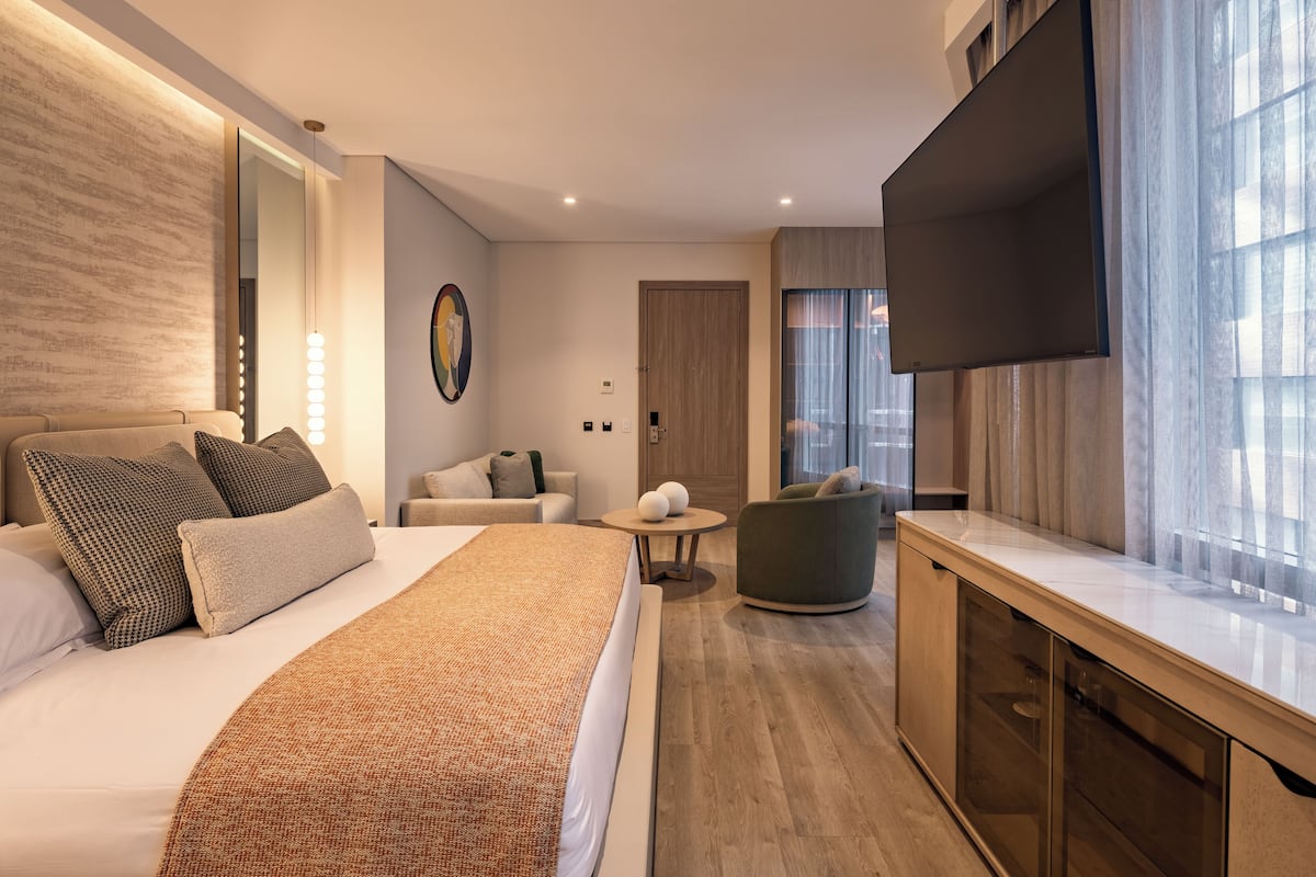 Una habitación de hotel moderna con una cama grande, un sofá, un televisor y un escritorio.