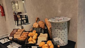 A buffet table with various baked goods, including bread, pastries, and croissants.