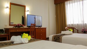 Habitación de hotel con dos camas, televisor, escritorio con computadora y espejo.
