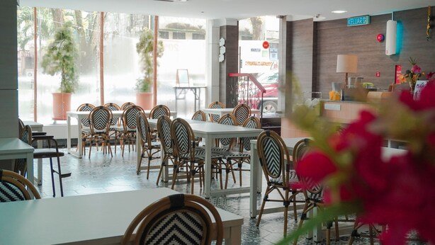 Un restaurante con mesas, sillas, una barra y vista a la calle.