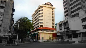 Un edificio de varios pisos con techo plano y balcones, rodeado de otros edificios.