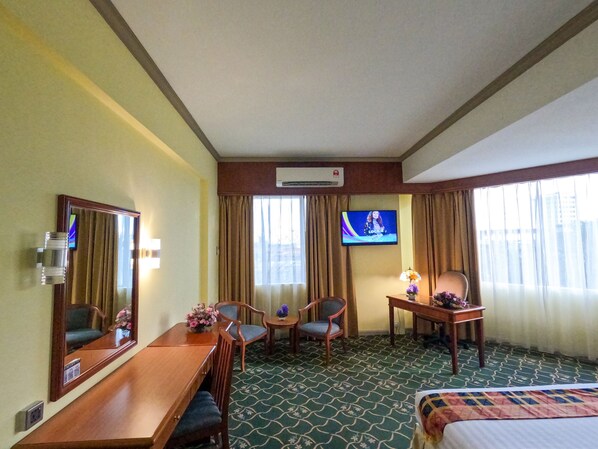 A hotel room with a bed, a desk, two chairs, a TV, and a mirror. - Hotel Sandakan (Sandakan)