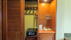 Una kitchenette compacta con microondas, cafetera y botellas de agua en una estantería.