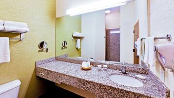 A bathroom with a granite countertop sink, a mirror, and a towel rack.