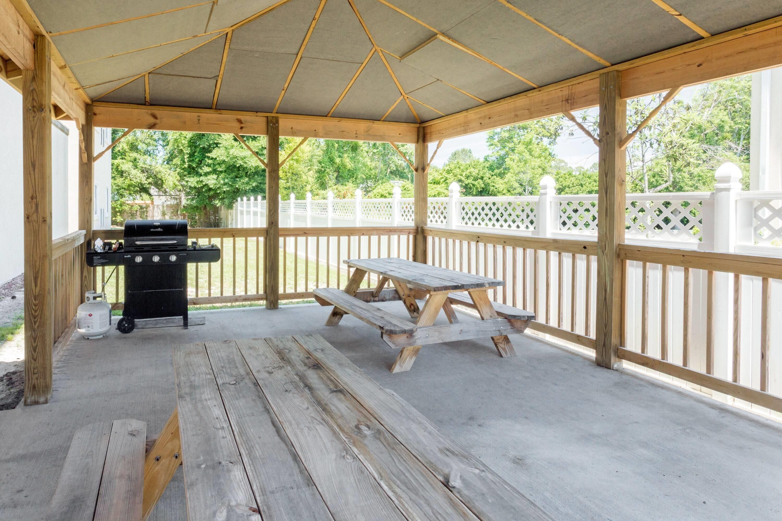 Un espacio al aire libre techado con una mesa de picnic y una parrilla.