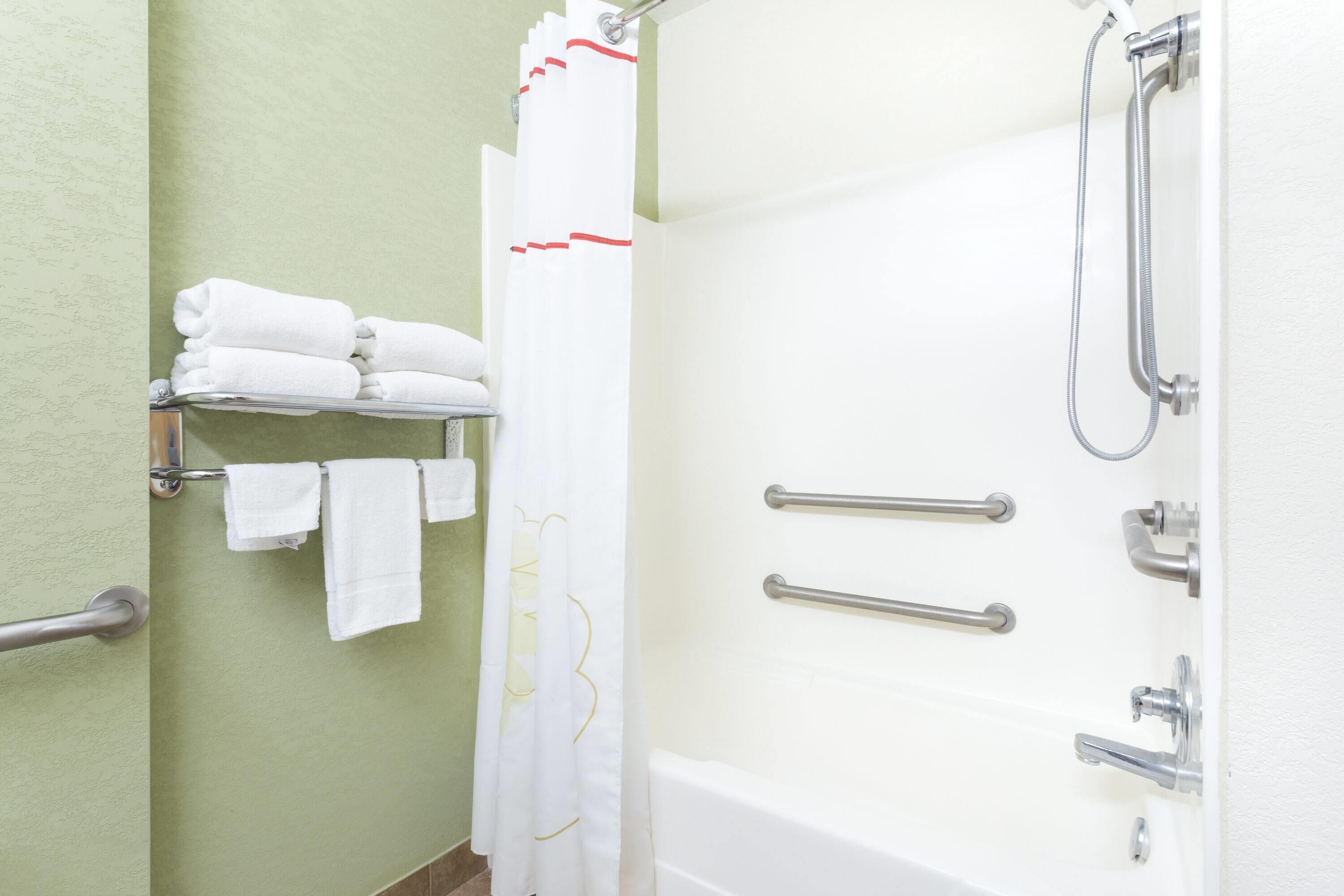A bathroom with a bathtub, a shower, a towel rack with folded towels, and a shower curtain.