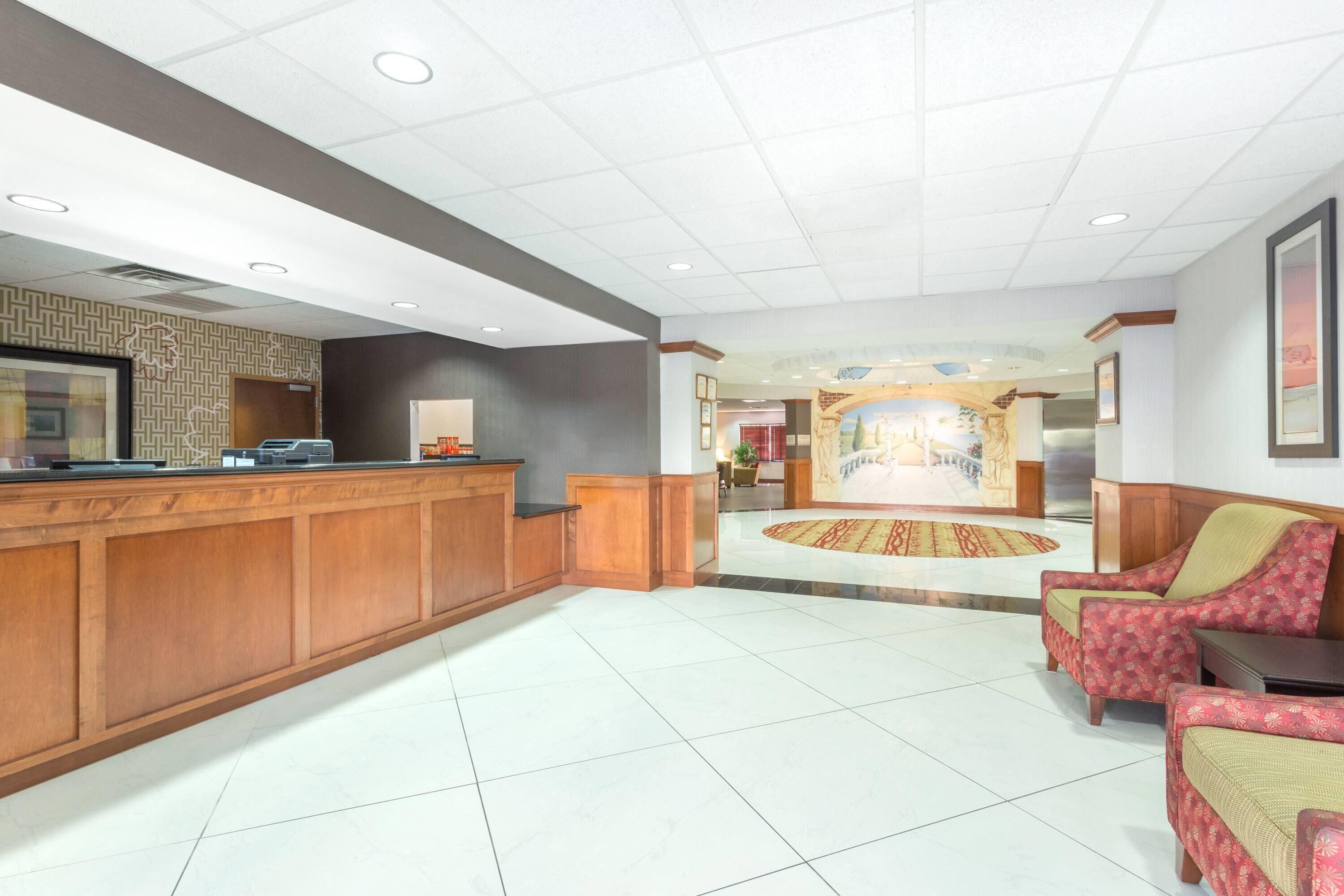A hotel lobby with a reception desk, seating area, and a central decorative wall.
