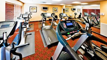 Un gimnasio con cintas de correr, bicicletas estáticas y máquinas elípticas.