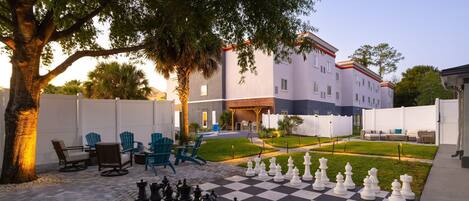 A courtyard with a chessboard, outdoor seating, and a building in the background.