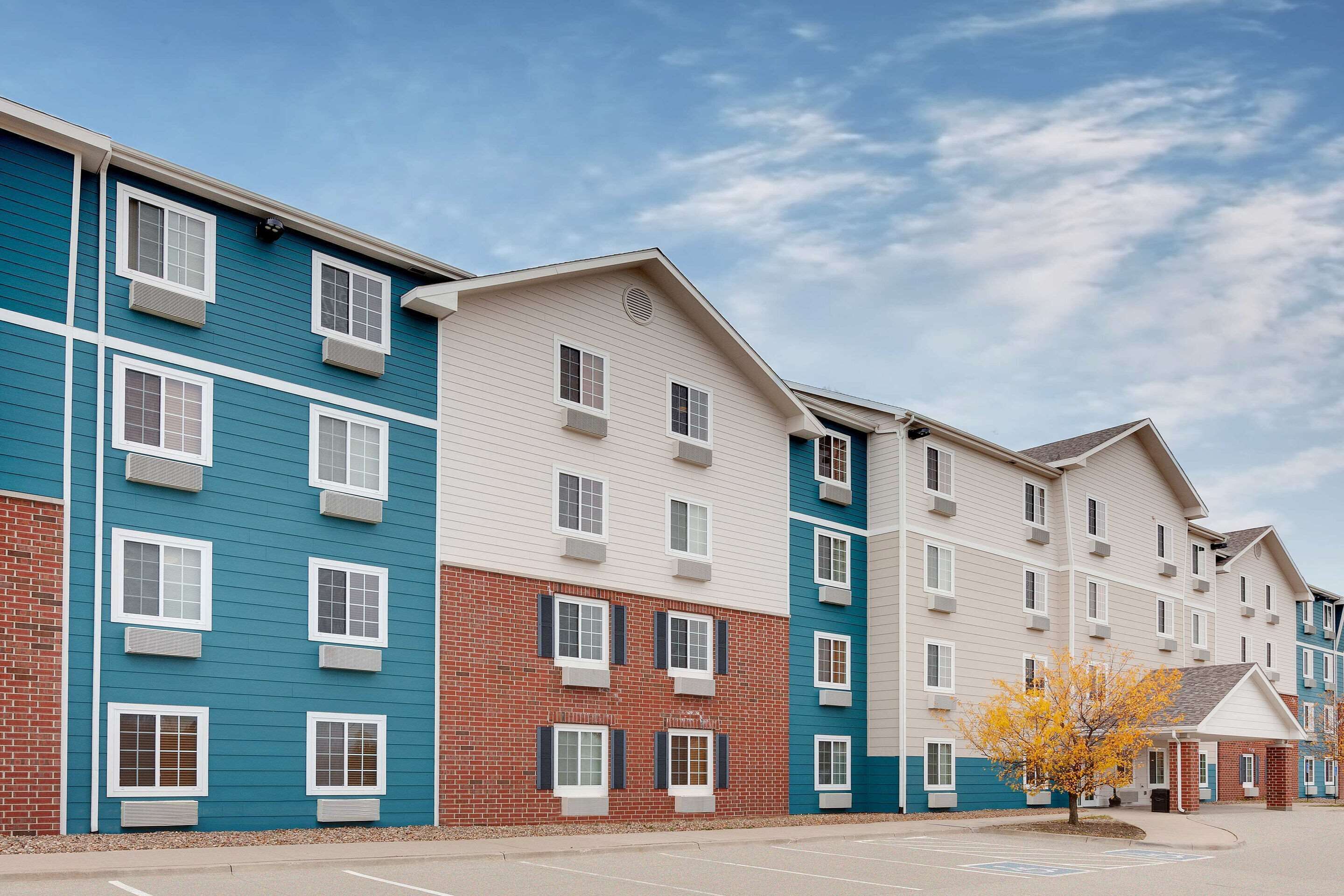 A row of multi-story residential buildings with a parking lot in front.