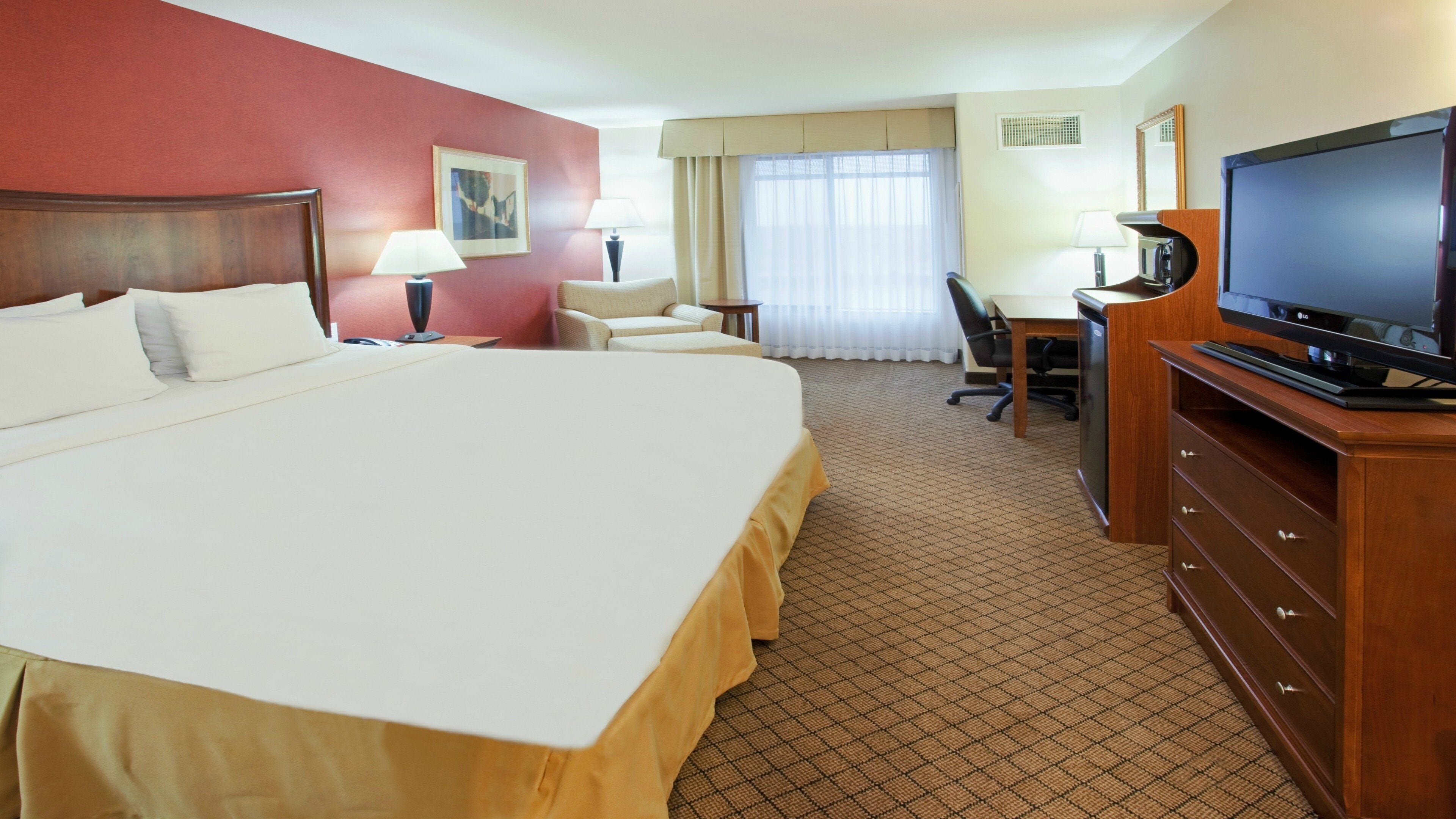 Una habitación de hotel con una cama grande, un escritorio, un televisor y una silla.