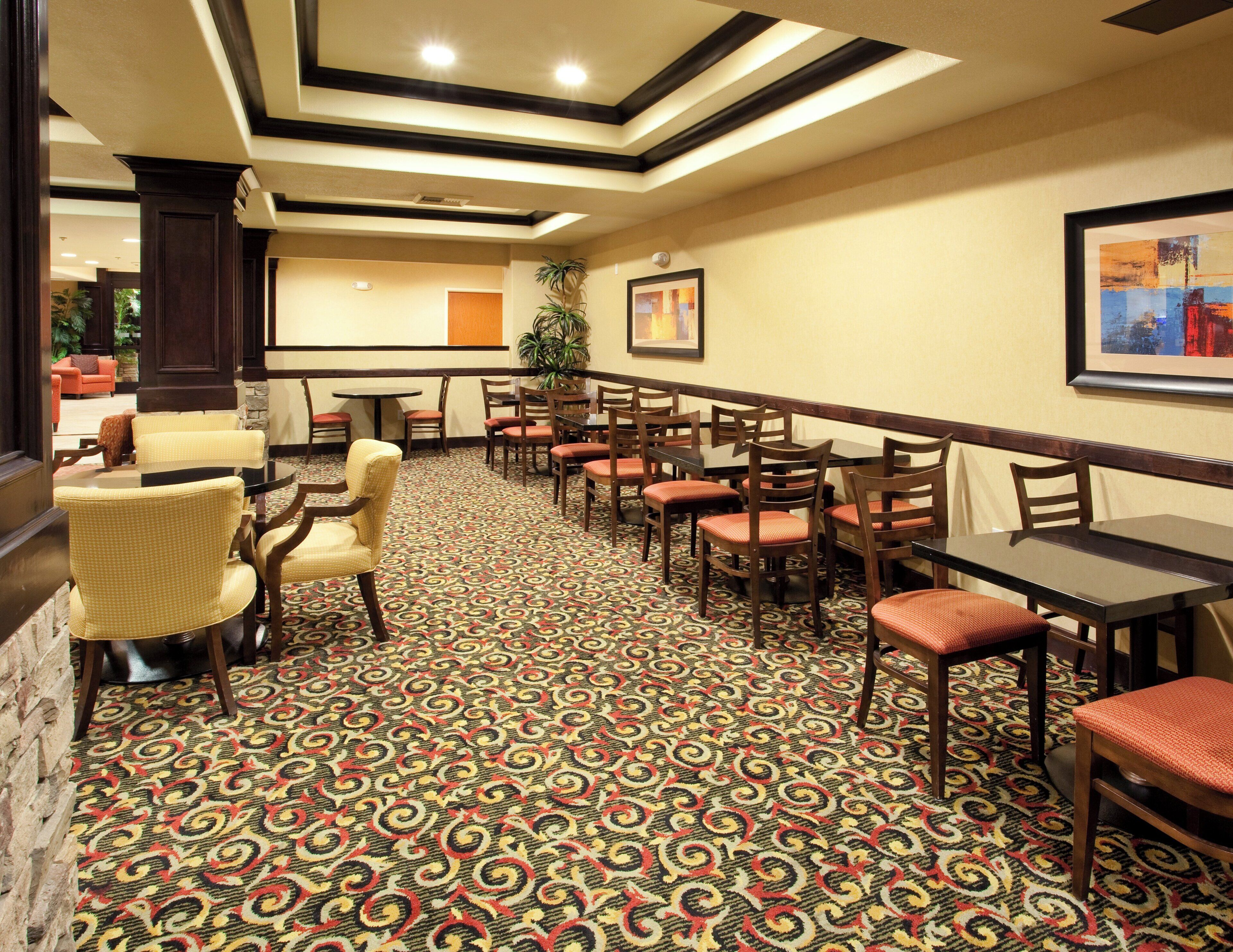 A hotel lobby with a patterned carpet, wooden furniture, and a framed picture on the wall.