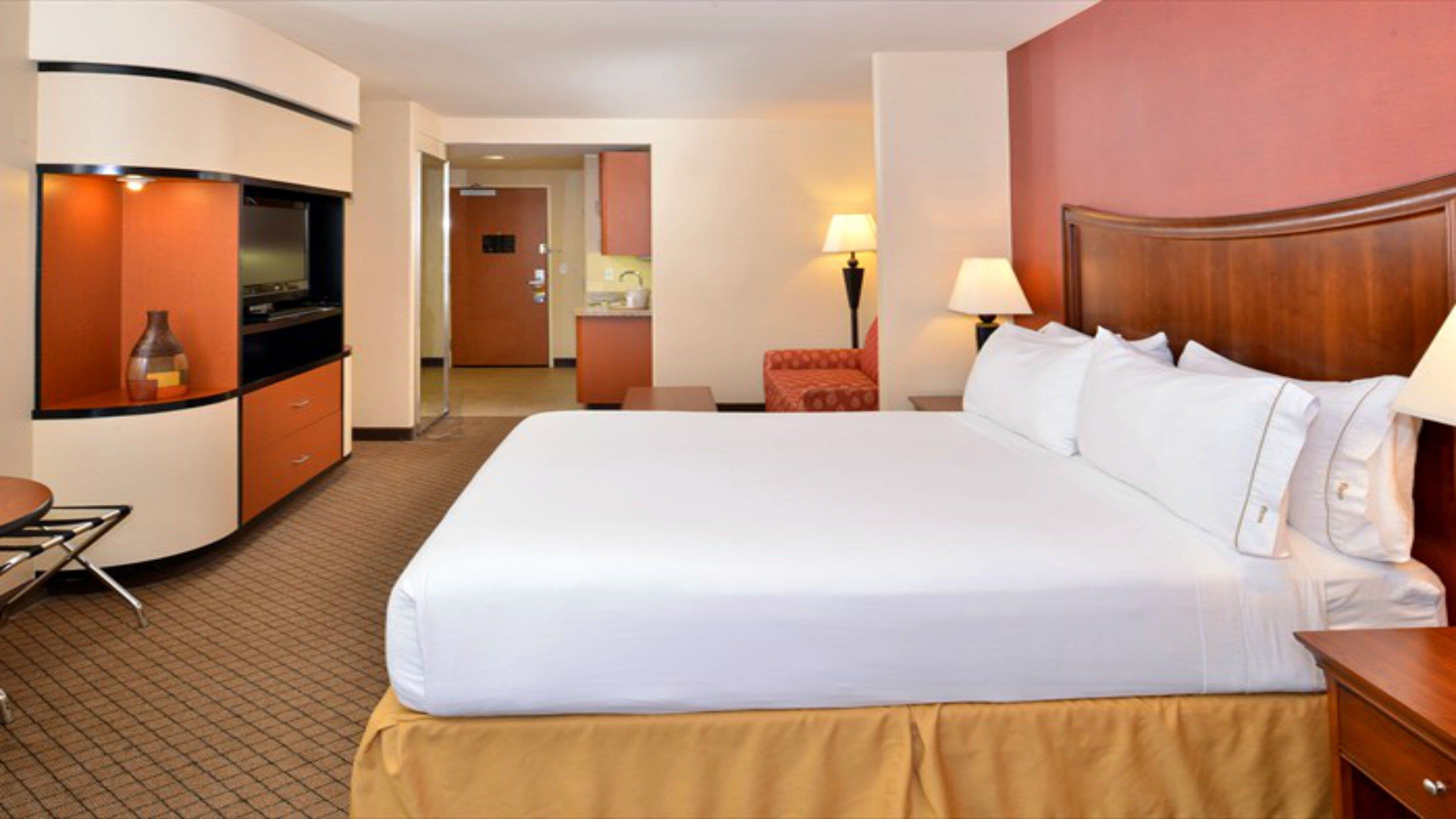 Une chambre d’hôtel équipée d’un grand lit, d’un bureau, d’une chaise, d’une télévision et d’un coin cuisine.