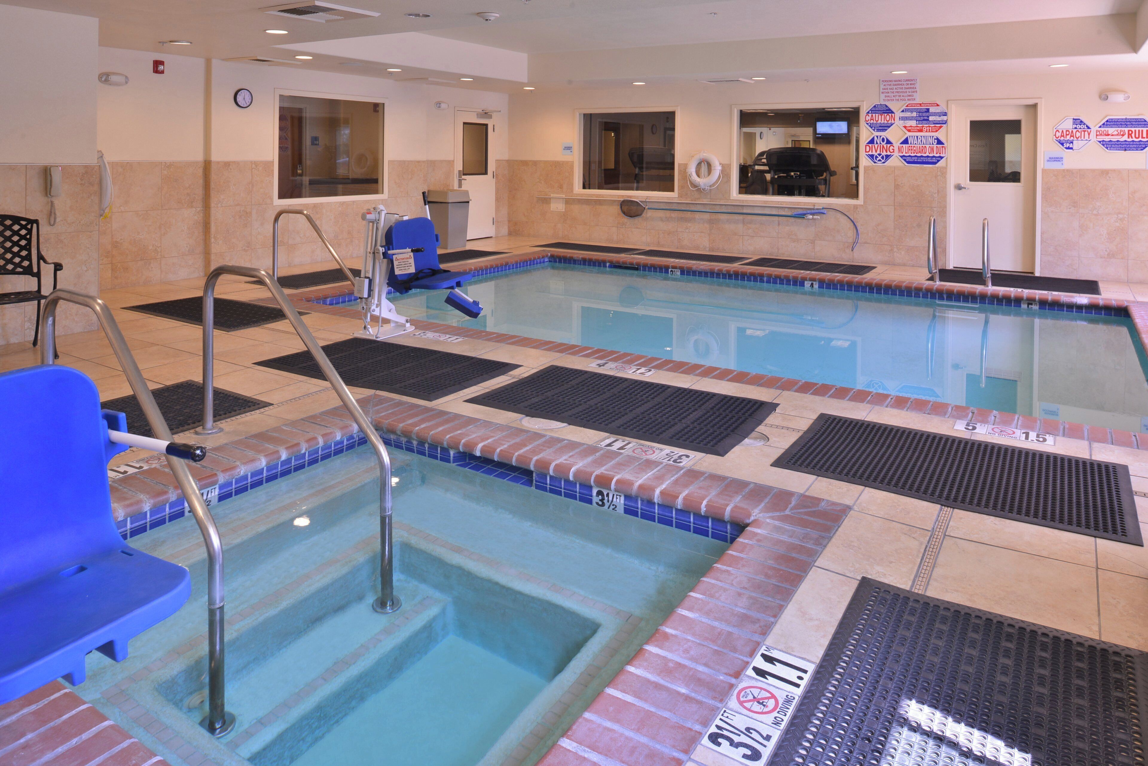A pool area with a lifeguard chair, a pool ladder, and a pool with a tiled edge.