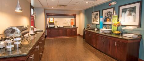 A hotel kitchen with wooden cabinets, granite countertops, and various appliances.