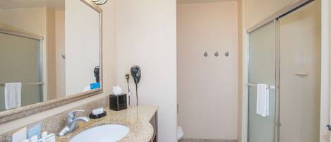 A bathroom with a sink, mirror, and a glass-enclosed shower.