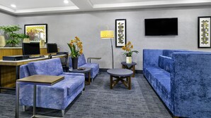 Um saguão de hotel com áreas de estar, um balcão de recepção e uma televisão.