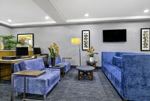 A hotel lobby with seating areas, a reception desk, and a television. - Holiday Inn Express Hotel & Suites Kansas City - Grandview by IHG (Grandview)