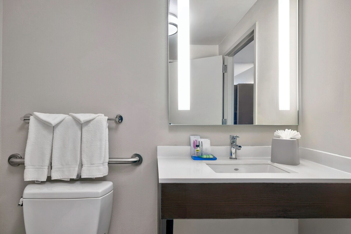 A modern bathroom with a toilet, a sink, a mirror, and a towel rack.