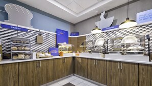 Un espace cuisine moderne avec des meubles en bois, un coin boulangerie et un comptoir de plats chauds.