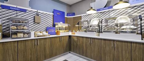 Una cocina moderna con armarios de madera, una sección de panadería y un mostrador de comida caliente.