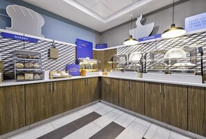 Un espace cuisine moderne avec des meubles en bois, un coin boulangerie et un comptoir de plats chauds.