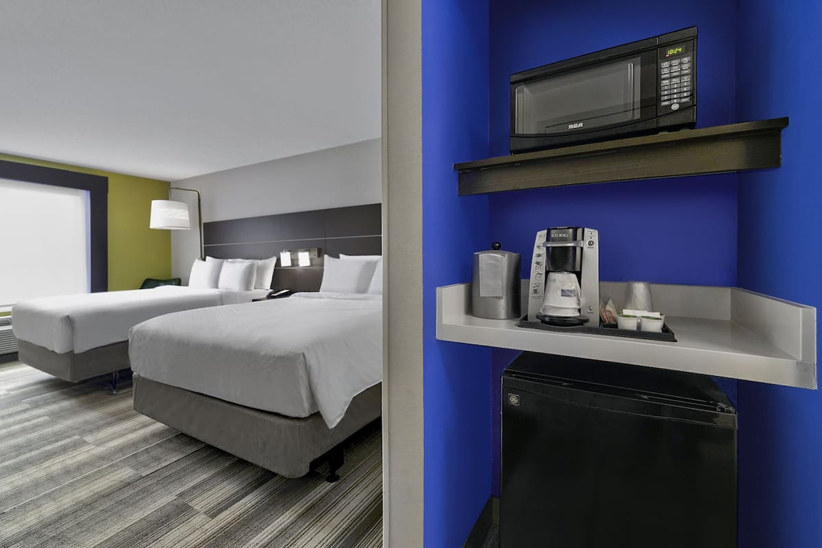 Une chambre d’hôtel avec deux lits, un four à micro-ondes, une machine à café et un petit réfrigérateur.