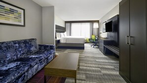 Une chambre d’hôtel équipée d’un canapé, d’un lit, d’un bureau, d’une télévision et d’une armoire.
