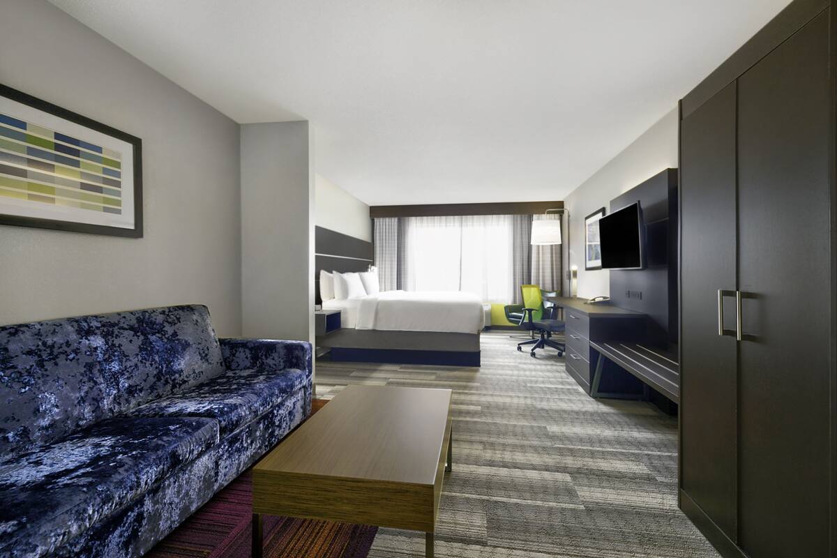 Une chambre d’hôtel équipée d’un canapé, d’un lit, d’un bureau, d’une télévision et d’une armoire.