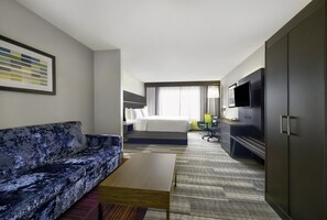 Une chambre d’hôtel équipée d’un canapé, d’un lit, d’un bureau, d’une télévision et d’une armoire.