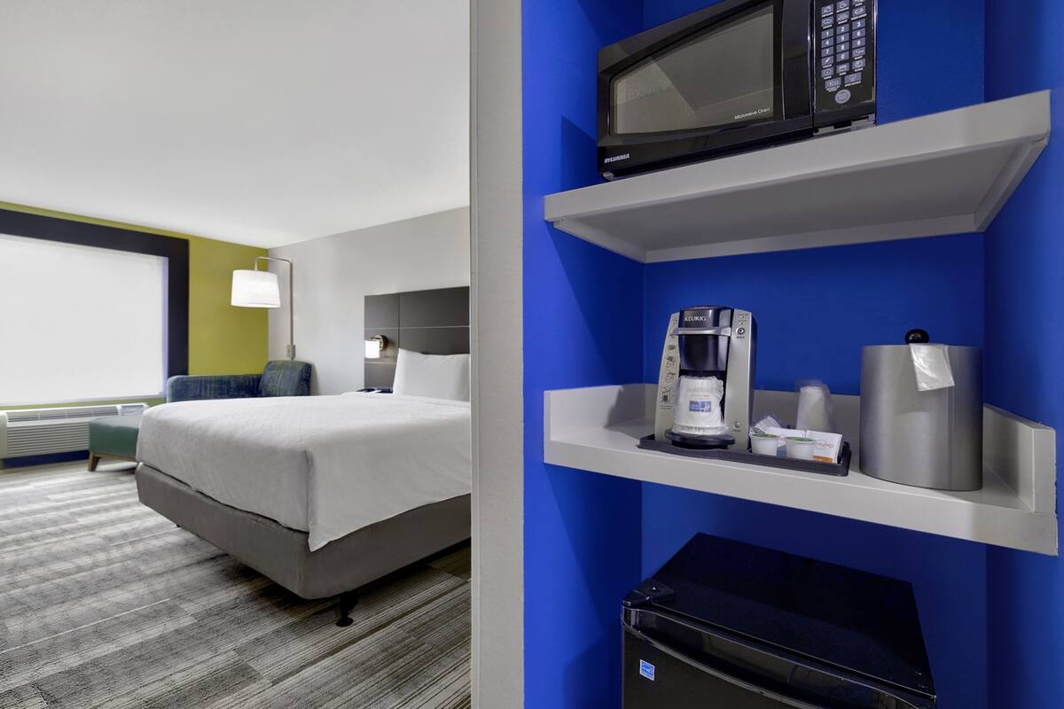 Une chambre d’hôtel équipée d’un lit, d’une machine à café, d’un four à micro-ondes et d’un petit réfrigérateur.