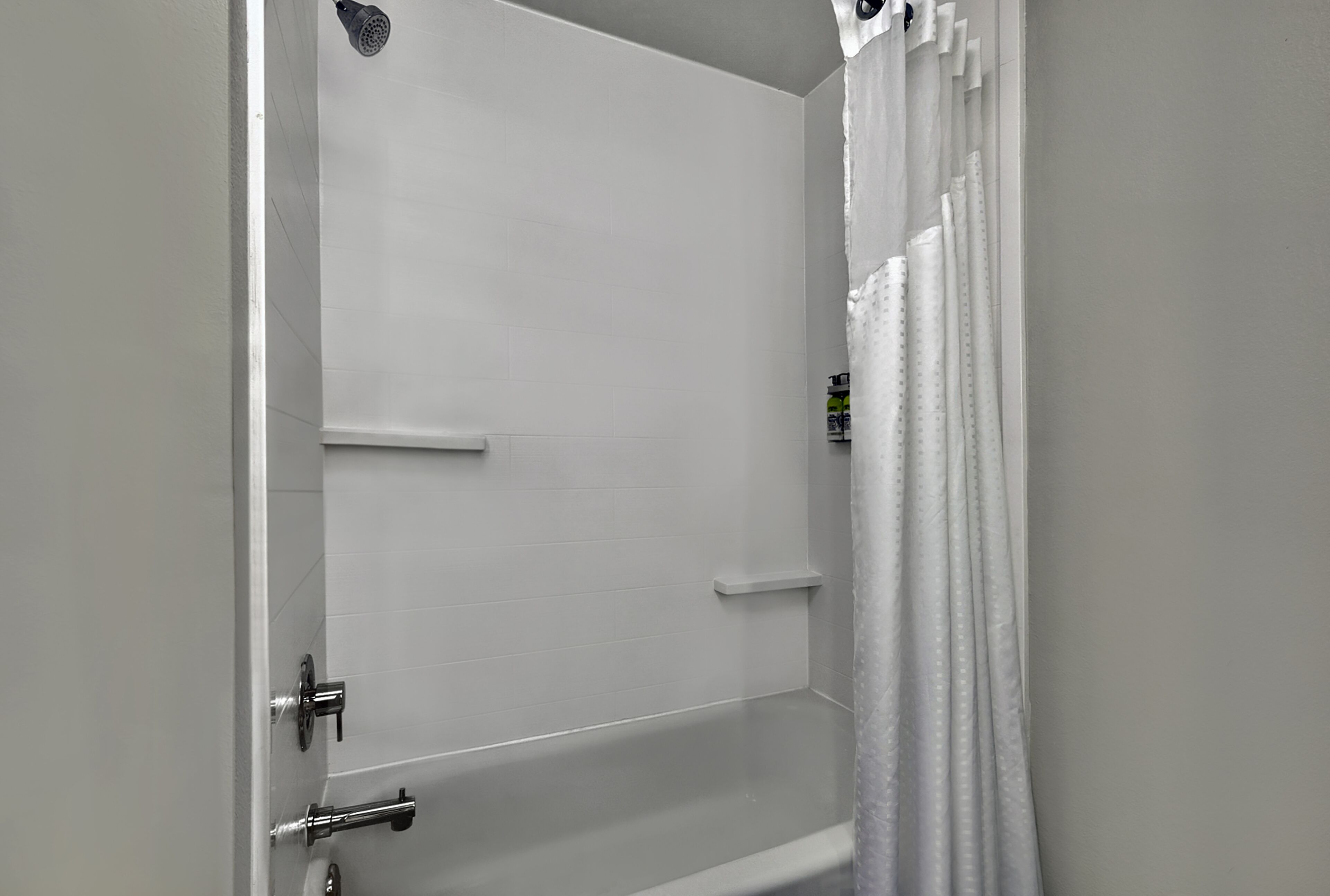 A bathroom with a bathtub, a showerhead, and a towel rack.