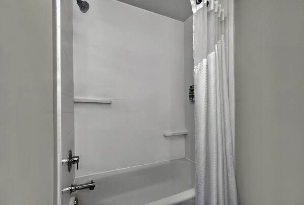 Un baño con bañera, cabezal de ducha y barra para toallas.