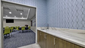 Quarto de hotel moderno com bancada de mármore, armários de madeira e papel de parede estampado.