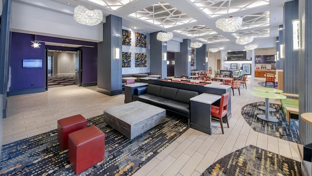 A modern lobby with a central seating area, a TV screen, and a patterned wall. - Hampton Inn & Suites Raleigh-Durham Airport-Brier Creek (Raleigh)