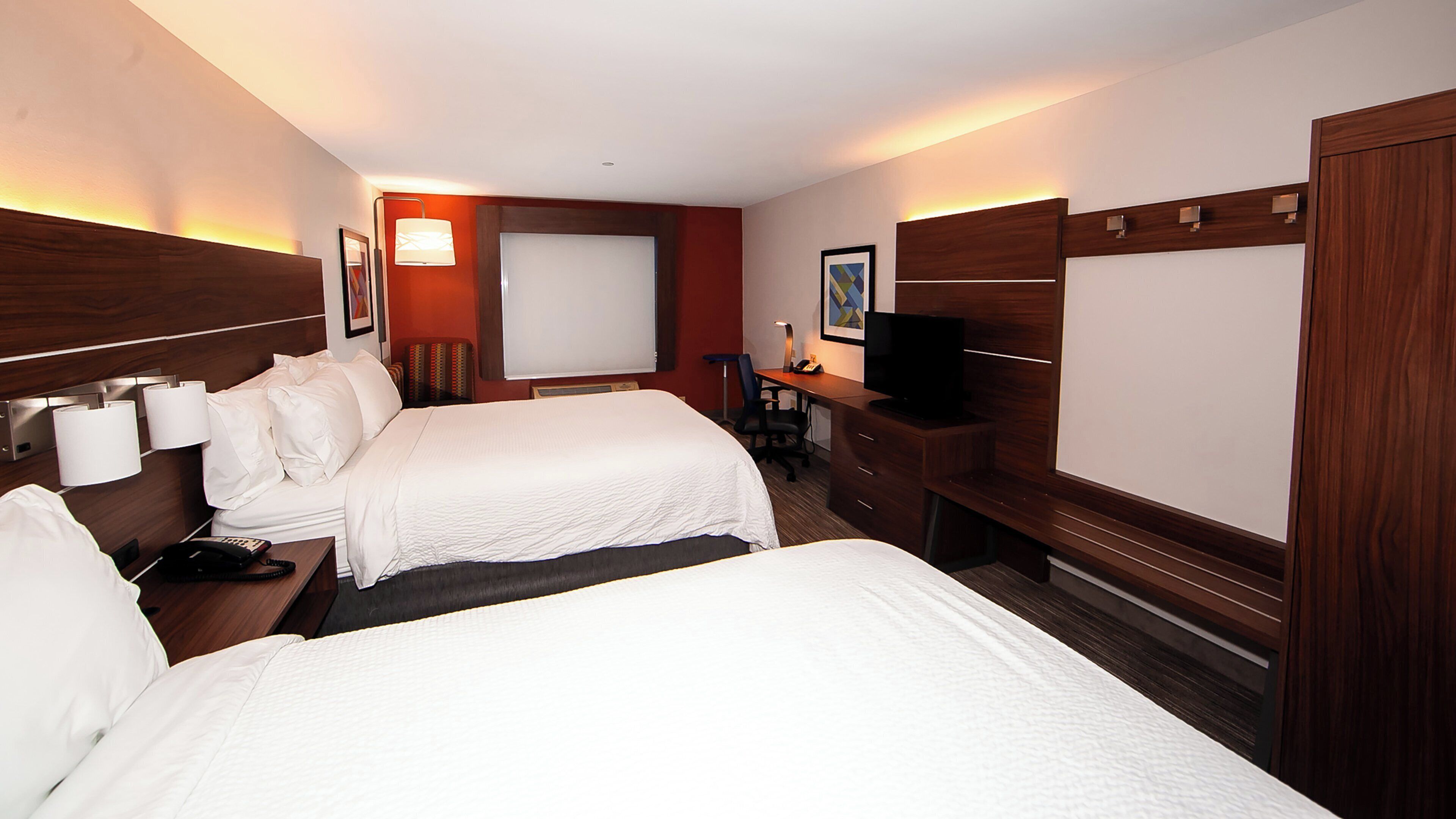 Une chambre d’hôtel avec deux lits, un bureau, une télévision et une chaise.