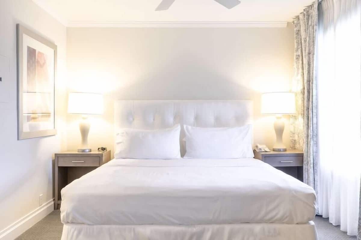 Une chambre d’hôtel avec un grand lit, deux tables de chevet et un ventilateur de plafond.